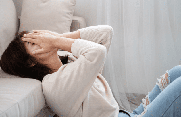 Person experiencing anxiety symptoms with hands on face, representing anxiety disorders.
