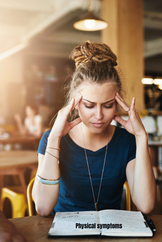 Young woman in a cafeteria holding her temples, showing stress and headache related to generalized anxiety disorder.