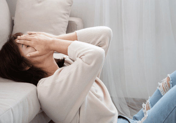 Person experiencing anxiety symptoms with hands on face, representing anxiety disorders.